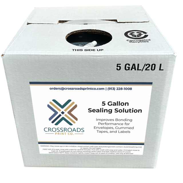 A white cardboard box of Crossroads Print Co. 5 Gallon Sealing Solution, with a large white label on the front and recycling symbols printed on the top surface.